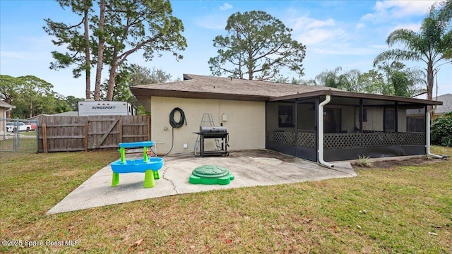 back of house with a patio area, a sunroom, and a lawn