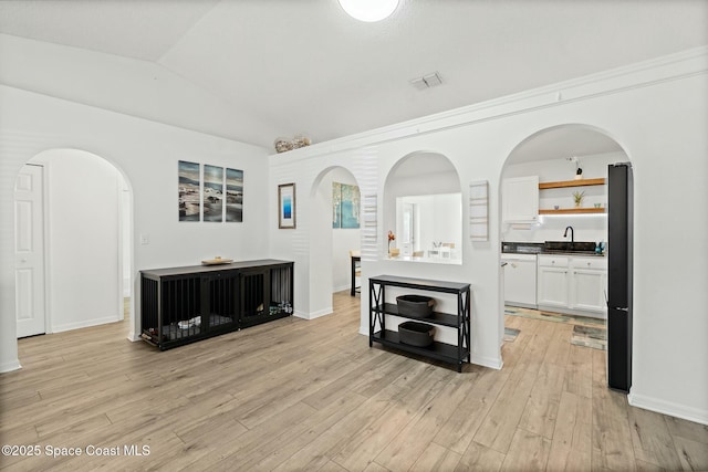 interior space with lofted ceiling, sink, and light hardwood / wood-style flooring