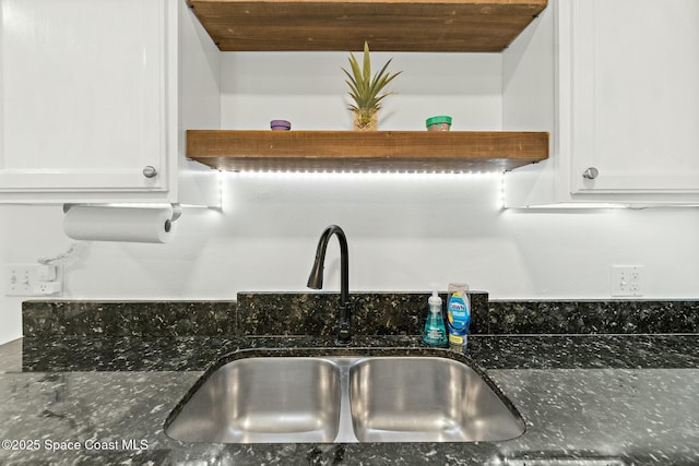 kitchen featuring white cabinetry, sink, and dark stone counters