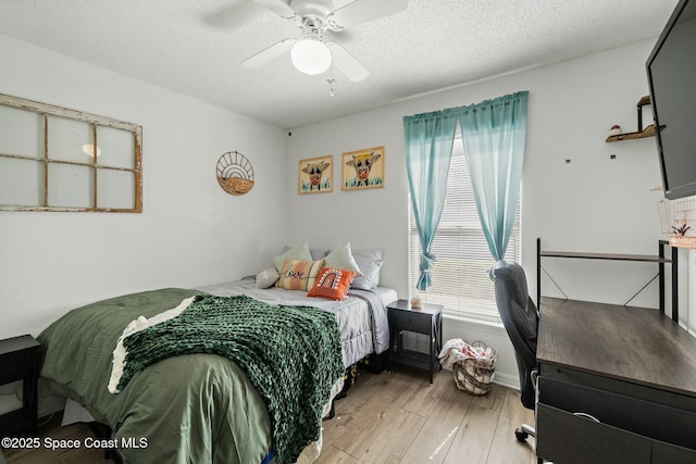 bedroom with ceiling fan, light hardwood / wood-style flooring, and a textured ceiling