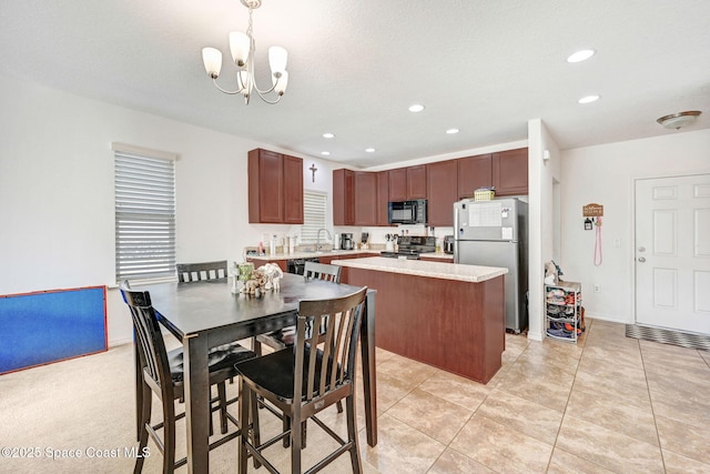 kitchen featuring sink, hanging light fixtures, a center island, black appliances, and an inviting chandelier