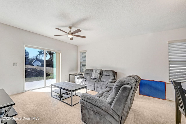 living room with ceiling fan, light carpet, and a textured ceiling