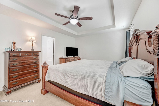 bedroom with light carpet, a raised ceiling, and ceiling fan