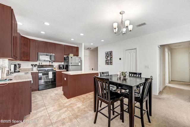 kitchen featuring a kitchen island, pendant lighting, sink, black appliances, and a textured ceiling