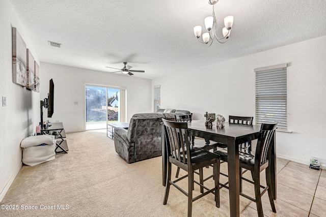 dining space with light carpet, ceiling fan with notable chandelier, and a textured ceiling