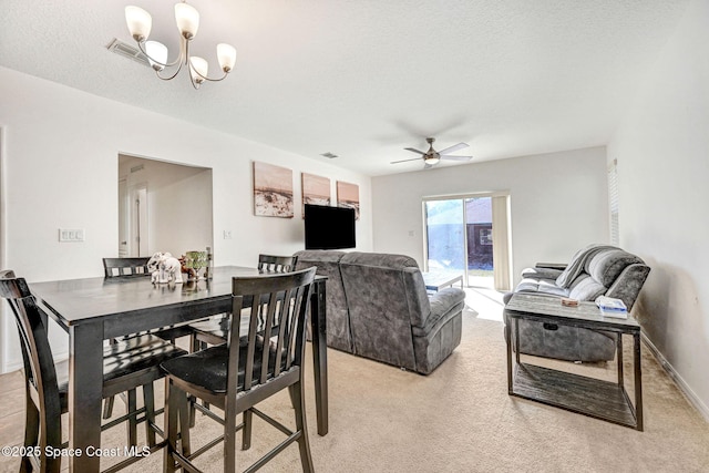 dining room with ceiling fan with notable chandelier, light carpet, and a textured ceiling