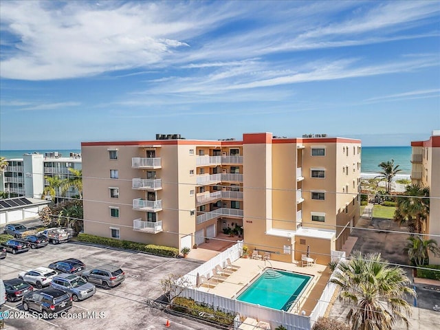 view of building exterior with a water view and a community pool