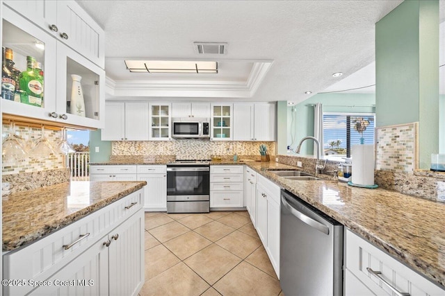 kitchen featuring sink, a tray ceiling, white cabinets, and appliances with stainless steel finishes