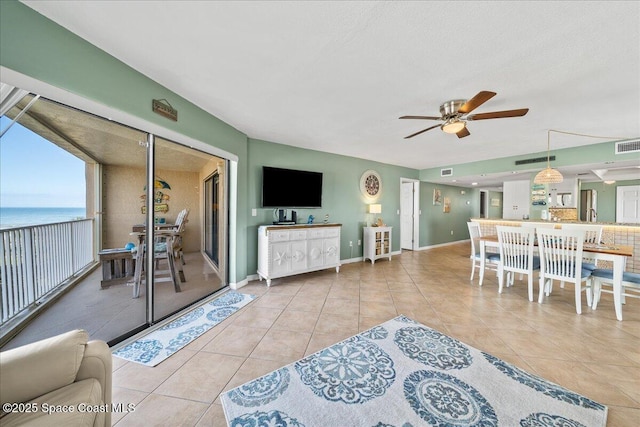 tiled living room with ceiling fan and a water view