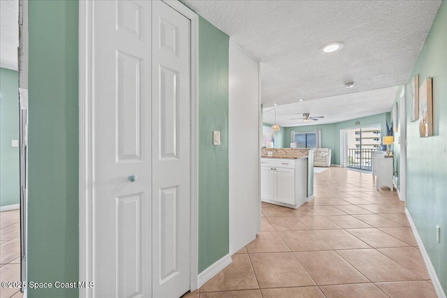 corridor with light tile patterned floors and a textured ceiling