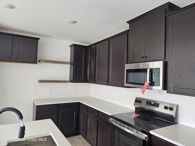 kitchen featuring sink, light hardwood / wood-style flooring, a textured ceiling, stainless steel appliances, and decorative backsplash