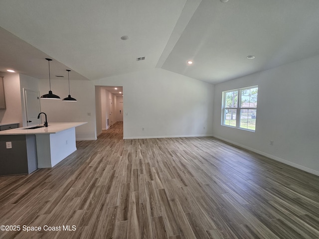 unfurnished living room featuring lofted ceiling, wood-type flooring, and sink