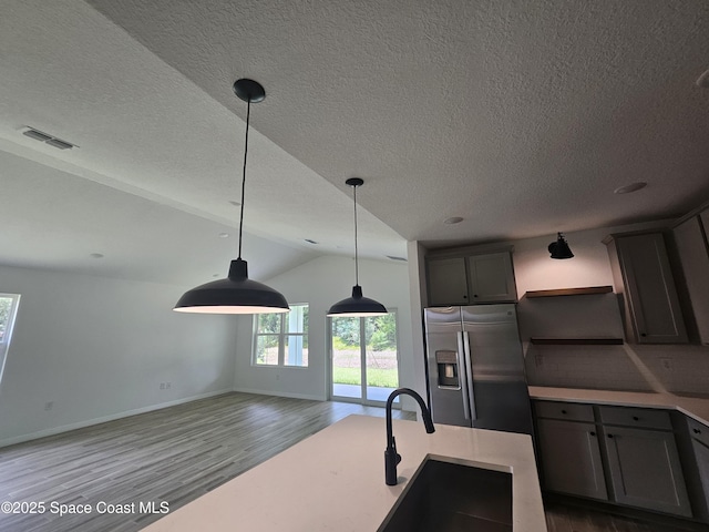 kitchen with sink, pendant lighting, stainless steel fridge with ice dispenser, hardwood / wood-style flooring, and backsplash