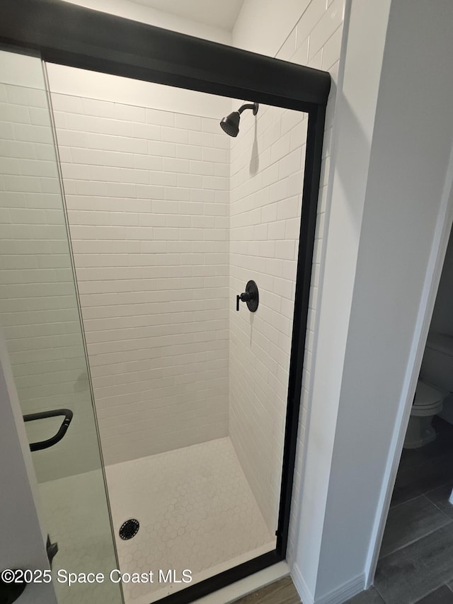 bathroom with a shower with shower door and toilet