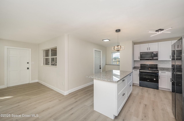 kitchen featuring white cabinetry, black electric range, hanging light fixtures, a kitchen island, and light stone countertops