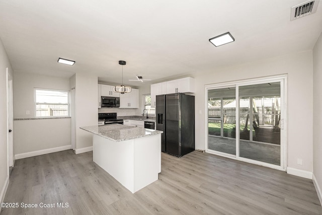 kitchen featuring pendant lighting, black appliances, light hardwood / wood-style floors, white cabinets, and a kitchen island