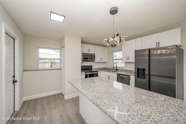 kitchen featuring sink, decorative light fixtures, stainless steel appliances, light stone countertops, and white cabinets