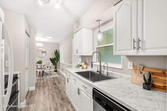 kitchen featuring decorative light fixtures, sink, white cabinets, double oven range, and light hardwood / wood-style floors