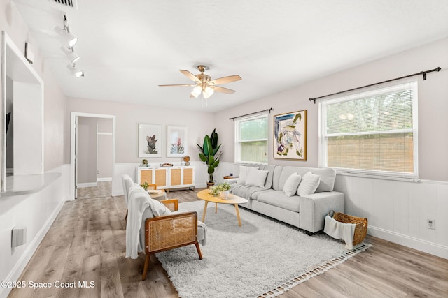 living room with light hardwood / wood-style flooring, rail lighting, and ceiling fan