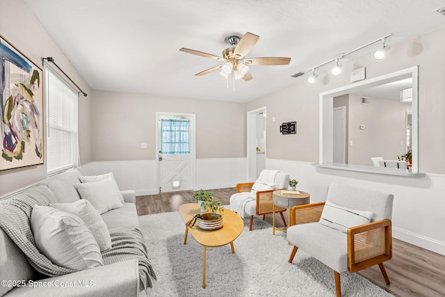 living room featuring hardwood / wood-style floors, track lighting, and ceiling fan