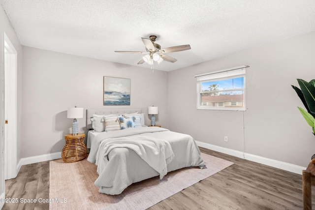 bedroom with wood-type flooring, ceiling fan, and a textured ceiling