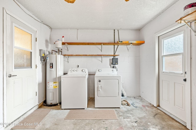 clothes washing area with washer and clothes dryer, water heater, and a textured ceiling