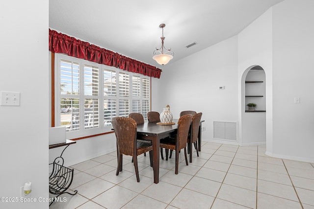 tiled dining room featuring built in shelves and vaulted ceiling