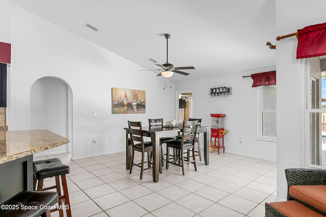 dining space with ceiling fan, lofted ceiling, a textured ceiling, and light tile patterned floors