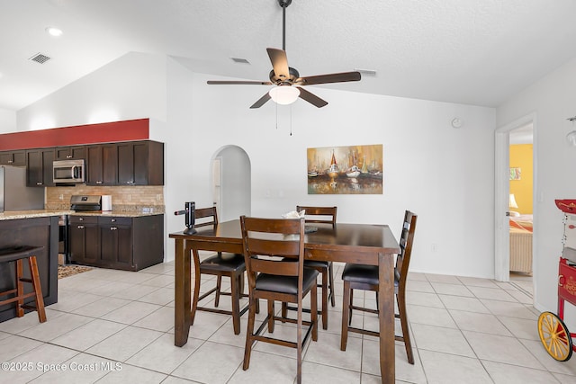 dining room with lofted ceiling, light tile patterned floors, a textured ceiling, and ceiling fan