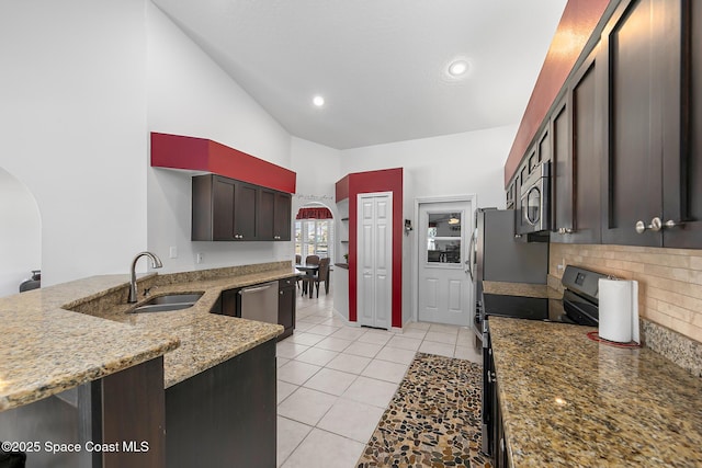 kitchen with sink, stainless steel appliances, dark brown cabinetry, light stone countertops, and decorative backsplash