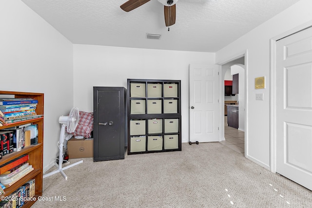 carpeted bedroom with ceiling fan and a textured ceiling