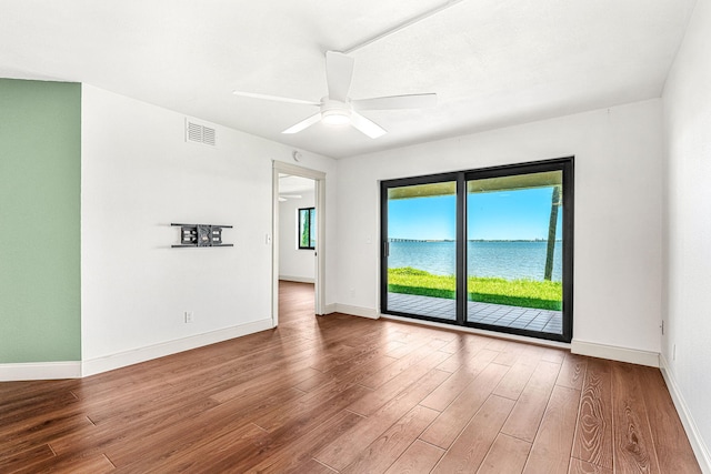 spare room with hardwood / wood-style floors, ceiling fan, and a water view