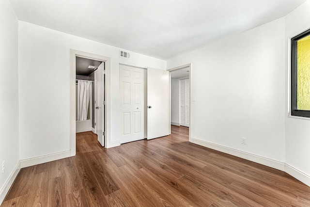 unfurnished bedroom with dark hardwood / wood-style floors and a closet