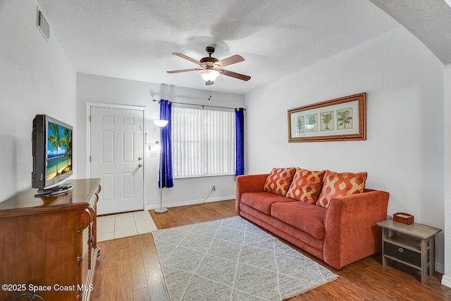 living room featuring hardwood / wood-style flooring, a textured ceiling, and ceiling fan