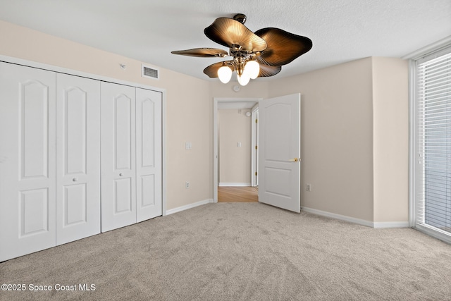 unfurnished bedroom with light colored carpet, ceiling fan, and a closet