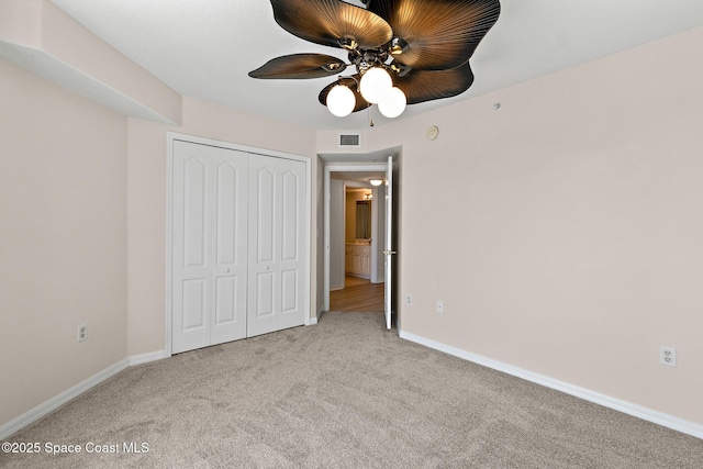 unfurnished bedroom with ceiling fan, a closet, and light carpet