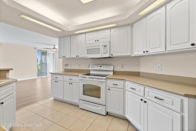 kitchen with white appliances, ceiling fan, white cabinetry, light tile patterned flooring, and a raised ceiling