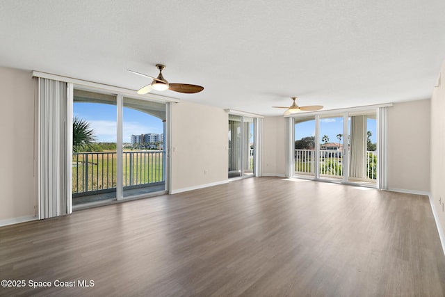 empty room with expansive windows, wood-type flooring, and a textured ceiling