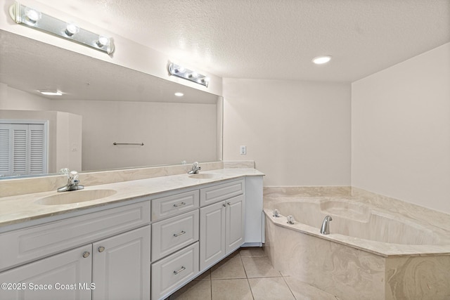 bathroom featuring vanity, tile patterned flooring, a textured ceiling, and a tub