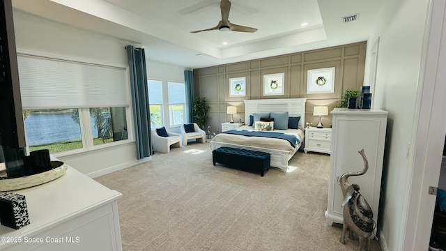 carpeted bedroom with a tray ceiling and ceiling fan