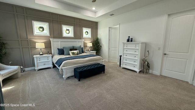 bedroom featuring a tray ceiling and light carpet