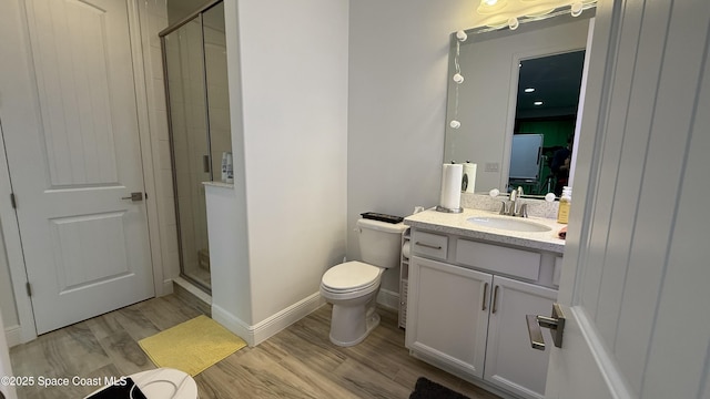 bathroom featuring vanity, toilet, hardwood / wood-style floors, and a shower with shower door