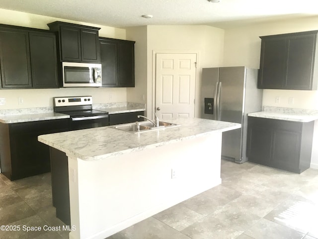 kitchen with sink, an island with sink, a textured ceiling, and appliances with stainless steel finishes