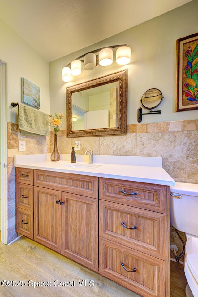 bathroom with vanity, toilet, and tile walls