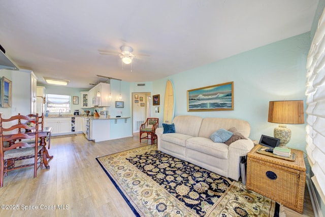 living room featuring sink, light hardwood / wood-style flooring, and ceiling fan