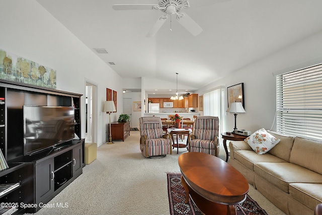 living room featuring lofted ceiling, ceiling fan with notable chandelier, and light colored carpet