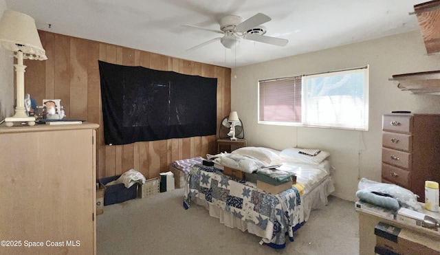 bedroom featuring ceiling fan, wooden walls, and light carpet