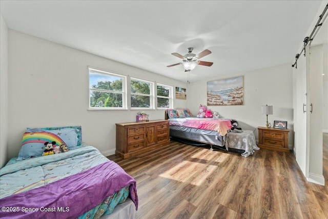 bedroom featuring hardwood / wood-style floors, a barn door, and ceiling fan