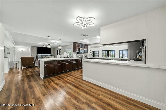 kitchen featuring stainless steel appliances, dark hardwood / wood-style floors, kitchen peninsula, and dark brown cabinets