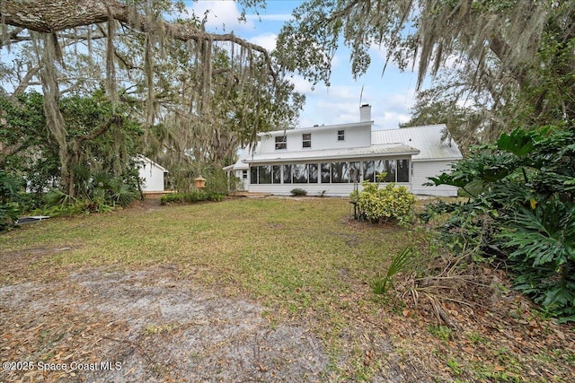 rear view of property with a yard and a sunroom